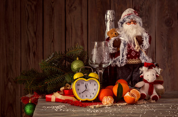 Fototapeta na wymiar The clock, Santa Claus, spruce branchs, tangerines, and champagne
