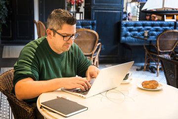 Businessman dressing a green sweeter doing his work in a nice cafe