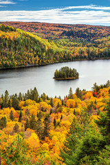 Obraz premium Jesienny leśny krajobraz jeziora z małą sosnową wyspą w Parku Narodowym La Mauricie, w prowincji Quebec w Kanadzie.