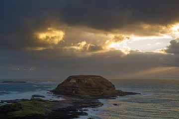 Shafts of Light breaking through dark clouds over the ocean. The Nobbies, Phillip Island Australia