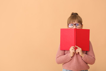 Cute little girl with book on color background