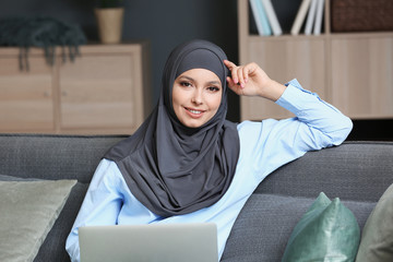 Beautiful Muslim student with laptop preparing for exam at home