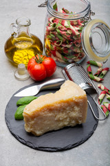 Cheese collection, piece of hard aged Italian parmesan or grana padano cheese with olive oil and tricolore italian pasta