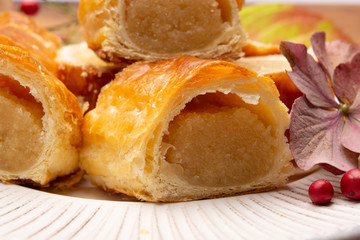 Fresh baked Dutch filled spicy cookies from puff pastry with almonds in autumn colors on dark wooden background