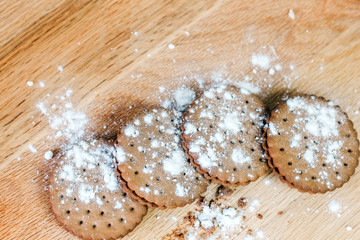 Crispy chocolate chip cookie with holes on a wooden board. Round cookies stuffed with powdered sugar