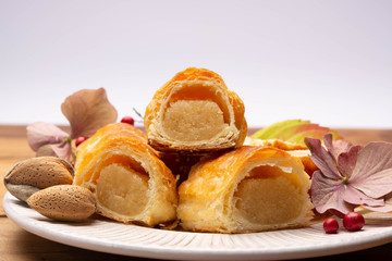 Fresh baked Dutch filled spicy cookies from puff pastry with almonds in autumn colors on dark wooden background