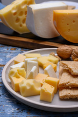 Tasty snacks, cheese blocks from Dutch yellow gouda and white goat hard cheeses and French holes cheese emmentaler