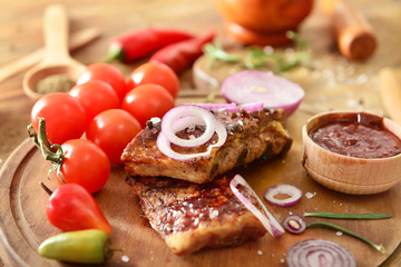 Tasty grilled meat with barbecue sauce, vegetables and spices on table