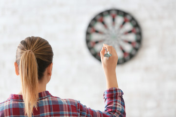 Young woman playing darts indoors