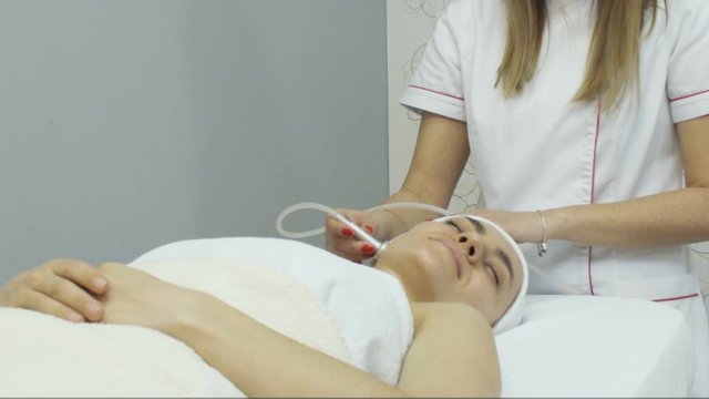 Young woman having oxygen facial treatment in beauty salon