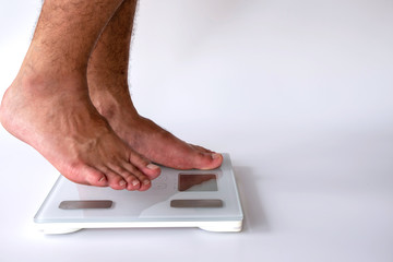 Fototapeta premium close-up of man feet on digital body fat analyzer scales on white background. fat burn and good health concept.