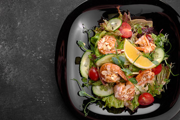 Vegetable salad with shrimp, on a black background