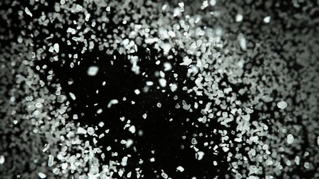 Super slow motion of flying whole grained salt pieces on black background. Filmed on high speed cinema camera, 1000 fps