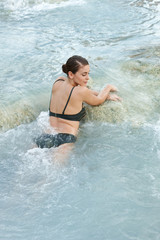 Pretty young brunette woman taking a bath in the natural geothermal waters of spa. Saturnia, Italy