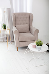 Classic soft armchair near the window in a room. Classic simple interior