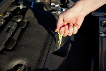 Men's hand holding the oil dipstick - checking the oil level