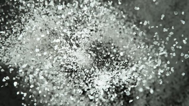 Super slow motion of flying whole grained salt pieces on black background. Filmed on high speed cinema camera, 1000 fps