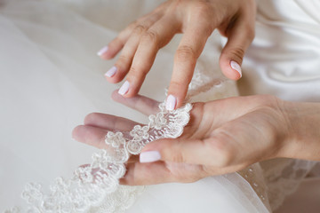 Bride's hand touching details of her wedding dress