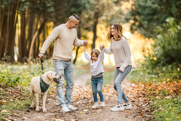 Happy beautiful family with dog labrador is having fun together walking the in park.