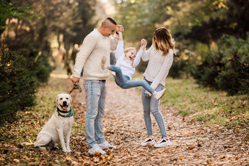 Fototapeta premium Happy beautiful family with dog labrador is having fun together walking the in park.
