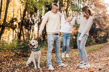 Fototapeta premium Happy beautiful family with dog labrador is having fun together walking the in park.