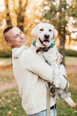Man holding on hands dog labrador in the park.