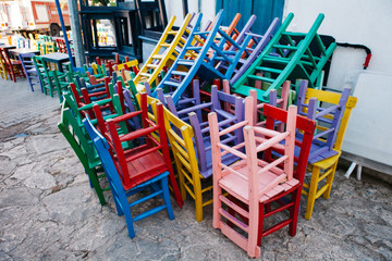 stacked colored wooden chairs. Lacquered wood chairs stacked out at a restaurant in a city street