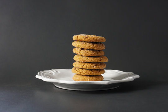 A Pile Of Chewy Gingerbread Cookies Stacked High On A White Plate With A Black Background