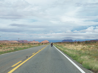 Lonely Biker on lonely Arizona desert road riding  to Monument Valley buttes