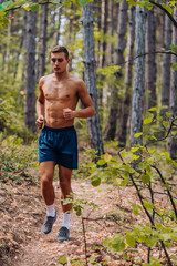 Muscular fit shirtless sport model sprinter exercising sprint on forest road