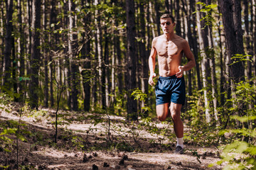 Full body portrait of a fit man running outdoors on a mountain path