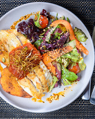 A serving of grilled fish with vegetables and salad