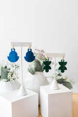 Two pairs of earrings on display, white background, copy space