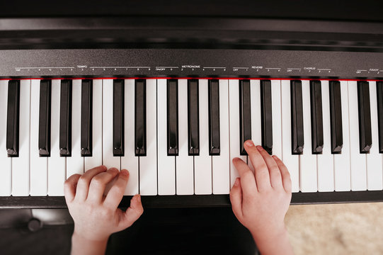 top view of hands playing on a synthesizer with white and black keys with musical term