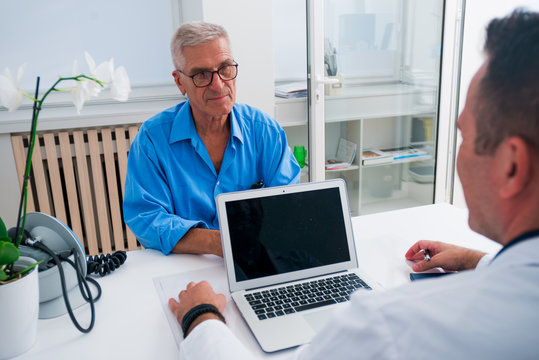 Handsome Doctor And His Senior (older) Patient Discussing The Symptoms The Older Gentleman Has, And The Illness He Might Have.