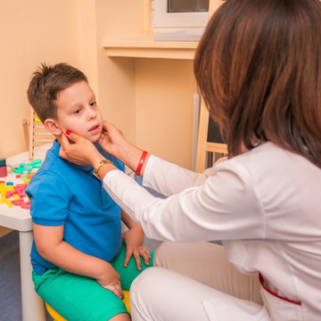 Female Pediatrician check's the throat and mouth of a young cute boy.