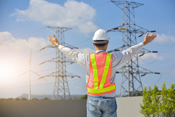 Electrical engineer standing holding his hand up Sky high voltage pole background