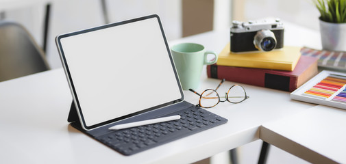 Close-up view of comfortable designer workspace with blank screen digital tablet and office supplies