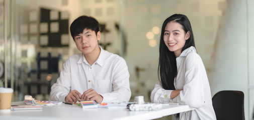 Portrait of two designer working on their project together while smiling to the camera