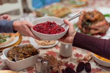 Passing a dish of homemade cranberry sauce at Thanksgiving dinner