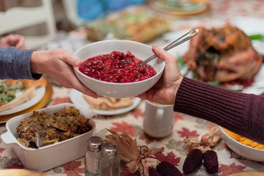 Passing A Dish Of Homemade Cranberry Sauce At Thanksgiving Dinner