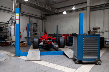 The process of repairing and restoring a red sports car at a pitstop in the service station or a...