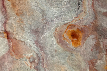 Background from a rough stone pattern on the wall with iridescent yellow, beige, orange and gray....