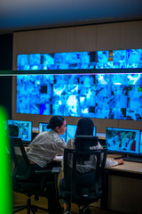 Female security guards working in surveillance room, monitoring cctv and discussing.