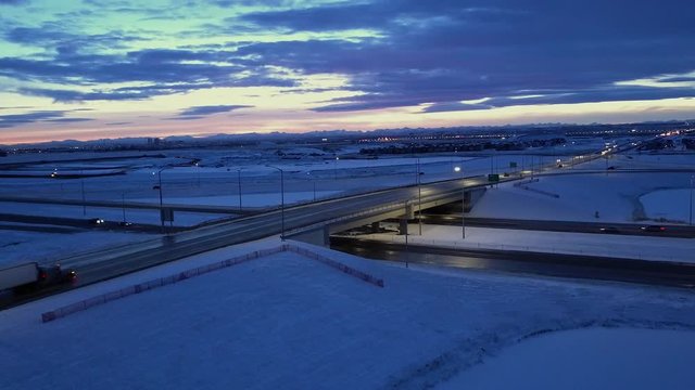 Dusk aerial of snowy overpass with lonely traffic and evening cloud