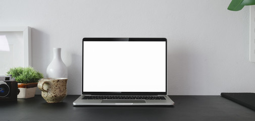 Cropped shot of open blank screen laptop computer with office supplies and copy space in modern office