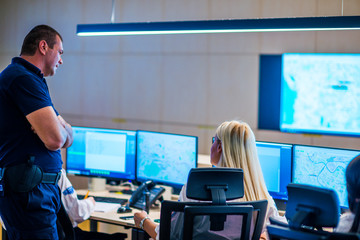 Security guards working in surveillance room, monitoring cctv and discussing.