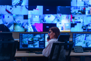 Team working on the System Control Room, Technical Operator Works at His Workstation with Multiple Displays, Security guards working on multiple monitors...