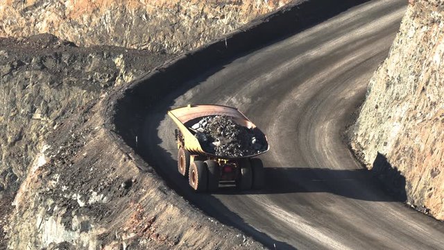 Western Australia / Australia - Circa 2000s: Large mining truck hauls rock and ore from depths of huge open cast mine pit. Mineral and metal mining concept. Late afternoon light. HOT AIR DISTORTION.