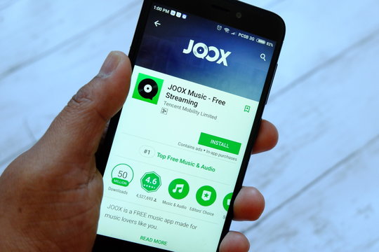 BANDAR SERI BEGAWAN,BRUNEI - JULY 25TH,2018 : A male hand holding smartphone with Joox app on an android Google Play Store